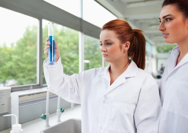 Science students looking at a graduated cylinder — Stock Photo, Image