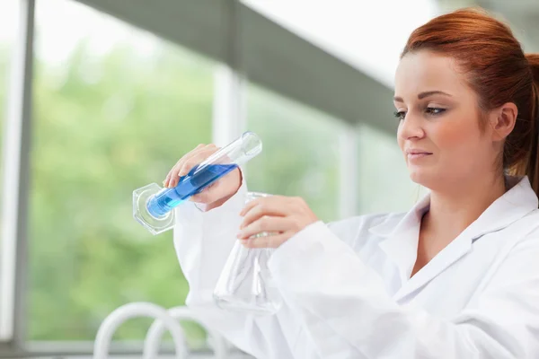 Science student pouring liquid in an Erlenmeyer flask — Stock Photo, Image