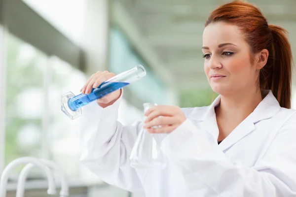 Científico vertiendo líquido en un frasco Erlenmeyer — Foto de Stock