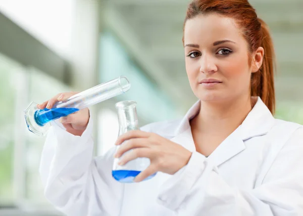 Lindo científico vertiendo líquido azul en un frasco Erlenmeyer —  Fotos de Stock