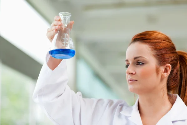 Científico mirando un líquido azul — Foto de Stock