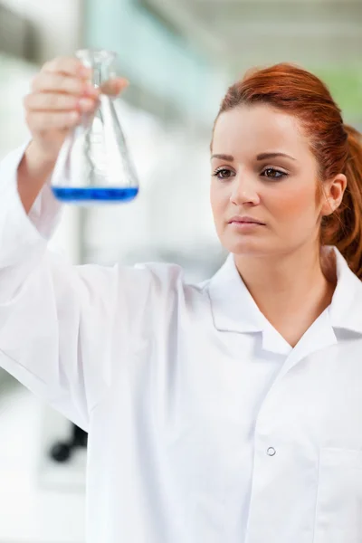 Retrato de um estudante de ciências olhando para um líquido azul — Fotografia de Stock