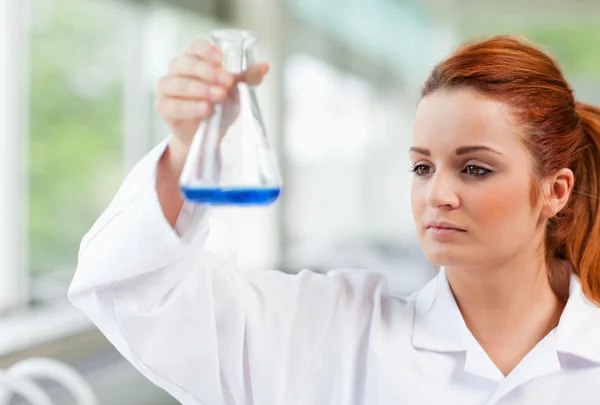Studentin der Naturwissenschaften blickt auf eine blaue Flüssigkeit — Stockfoto