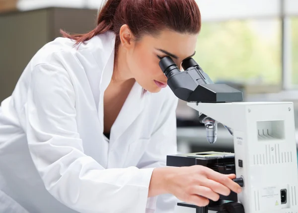 Un jeune scientifique examine un microscope — Photo