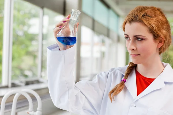 Químico olhando para um líquido azul — Fotografia de Stock
