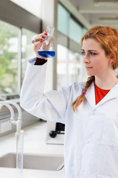 Portrait of a chemist looking at a blue liquid — Stock Photo, Image