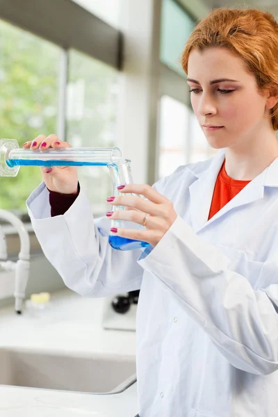 Portrait of a red-haired scientist pouring liquid — Stock Photo, Image