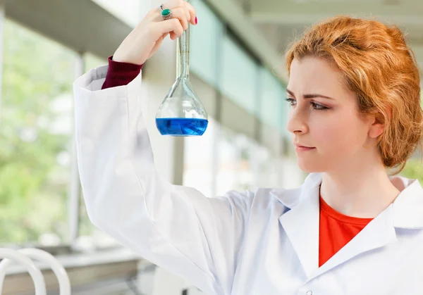 Cute scientist holding a blue liquid — Stock Photo, Image