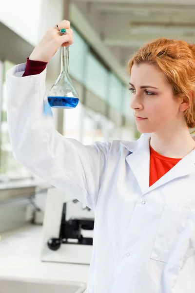 Porträtt av en söt forskare håller en blå vätska — Stockfoto
