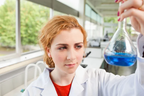 Lindo estudiante de ciencias sosteniendo un líquido azul — Foto de Stock