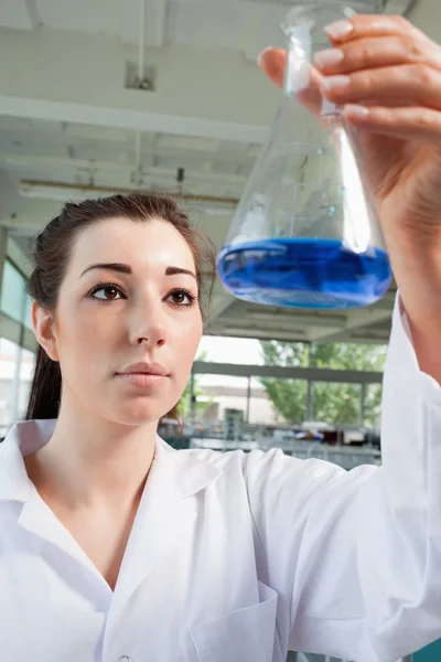 Portrait of a brunette looking at a blue liquid — Stock Photo, Image