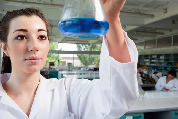 Студент-физик смотрит на голубую жидкость — стоковое фото