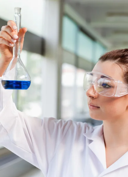 Portrét mladé vědy studenta při pohledu na modrou tekutinu — Stock fotografie