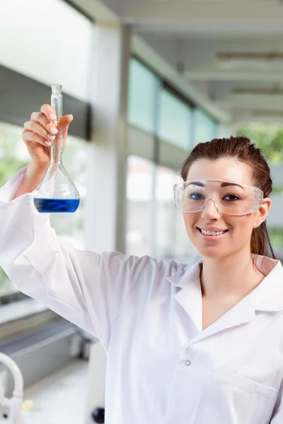 Retrato de uma estudante de ciências feminina segurando um líquido azul — Fotografia de Stock