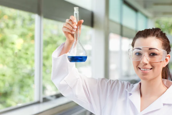 Samice věda student držící modrou tekutinu — Stock fotografie
