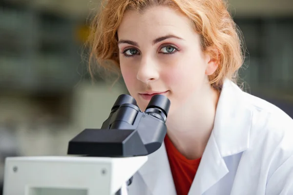 Primer plano de un joven estudiante posando con un microscopio — Foto de Stock