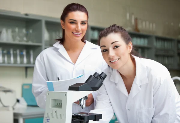Naturwissenschaftsstudenten posieren mit einem Mikroskop — Stockfoto