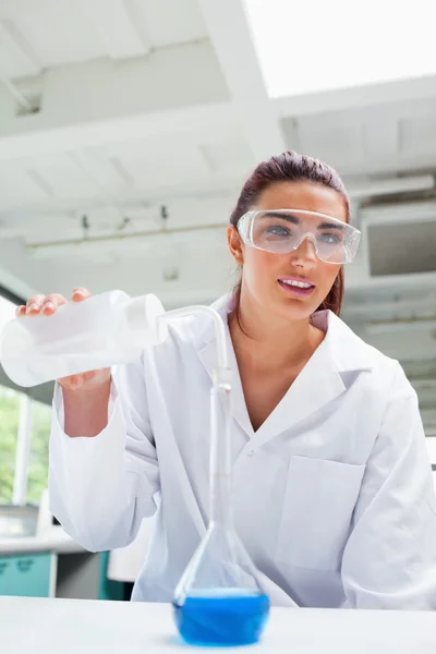 Retrato de uma estudante de ciências do sexo feminino derramando líquido com proteger — Fotografia de Stock