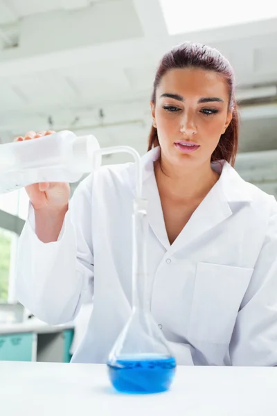 Retrato de uma cientista feminina derramando líquido — Fotografia de Stock
