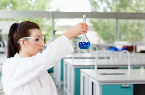 Morena cientista olhando para um frasco — Fotografia de Stock