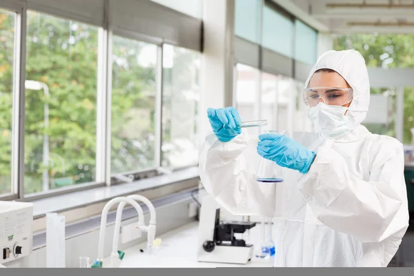 Beschermde vrouwelijke wetenschapper die vloeistof in een erlenmeyer giet — Stockfoto