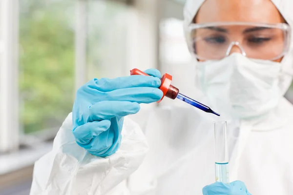 Protected scientist dropping a liquid in a test tube — Stock Photo, Image