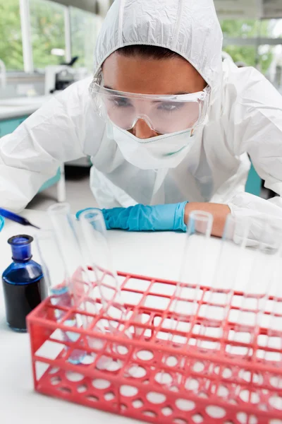 Portrait of a protected female scientist dropping blue liquid in — Stock Photo, Image