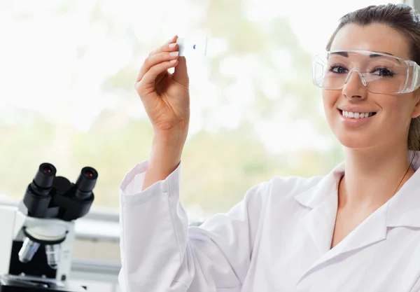 Estudiante de ciencias sonriente sosteniendo una diapositiva de microscopio — Foto de Stock