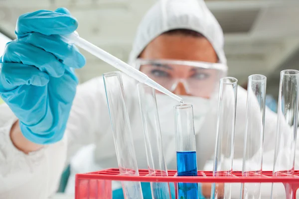 Close up of a protected scientist dropping liquid in a test tube — Stock Photo, Image