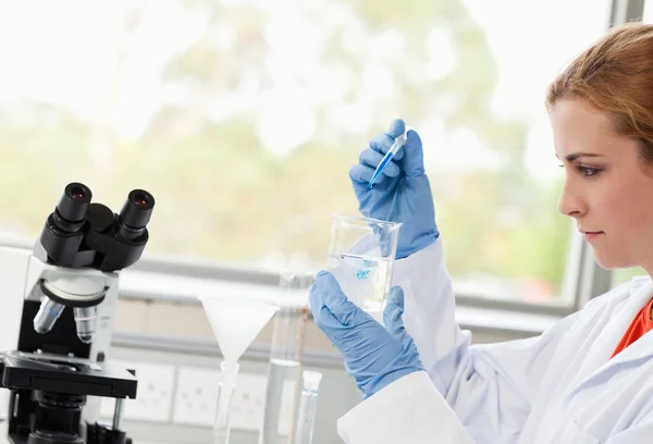 Science student dropping liquid in a beaker — Stock Photo, Image