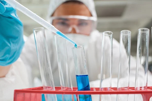 Estudante de ciências protegido soltando líquido azul em um tubo de teste — Fotografia de Stock