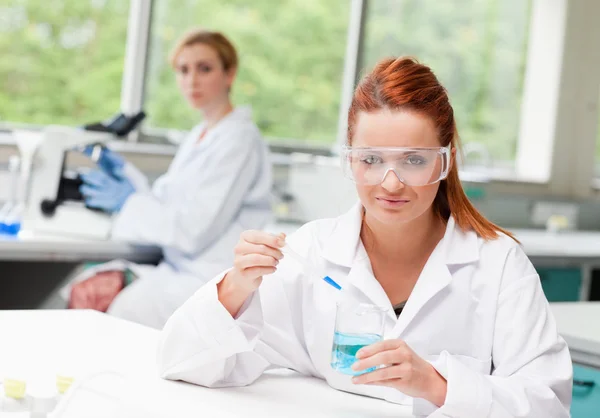 科学家在一个烧杯中滴液体，而她的同事是富联国际 — 图库照片