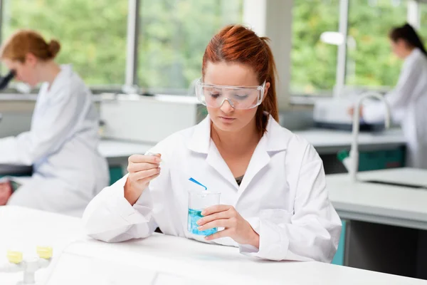 Wetenschap student vloeistof te laten vallen in een bekerglas van terwijl haar klasgenoten — Stockfoto