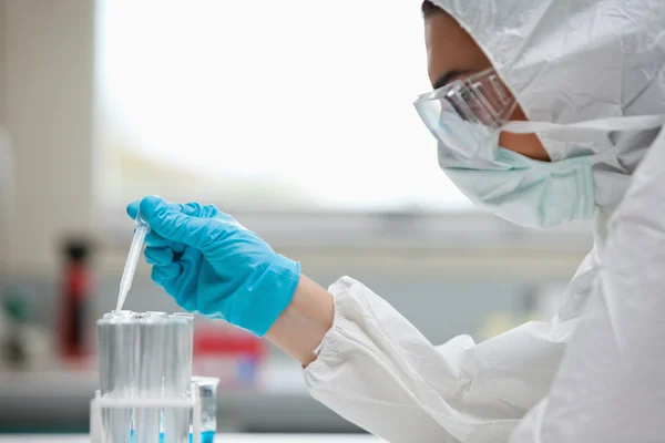 Close up of a protected female scientist dropping liquid in a te — Stock Photo, Image