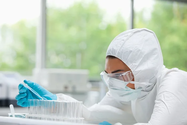 Protected female scientist dropping liquid in a test tube — Stock Photo, Image