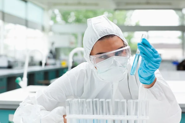 Protected female scientist looking at a test tube — Stock Photo, Image