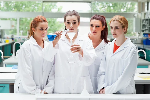 Vetenskap studenter hälla vätska i en kolv — Stockfoto
