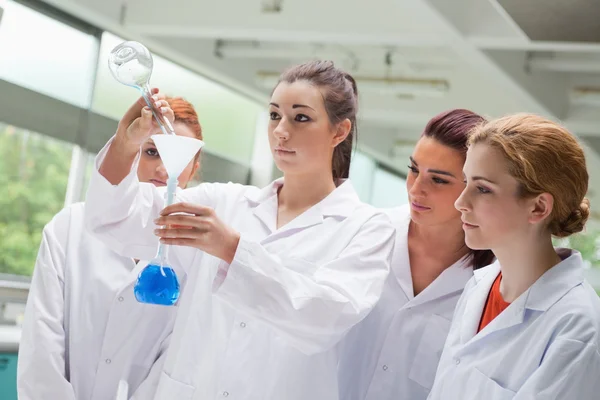 Lindos estudiantes de ciencias vertiendo líquido en un frasco —  Fotos de Stock