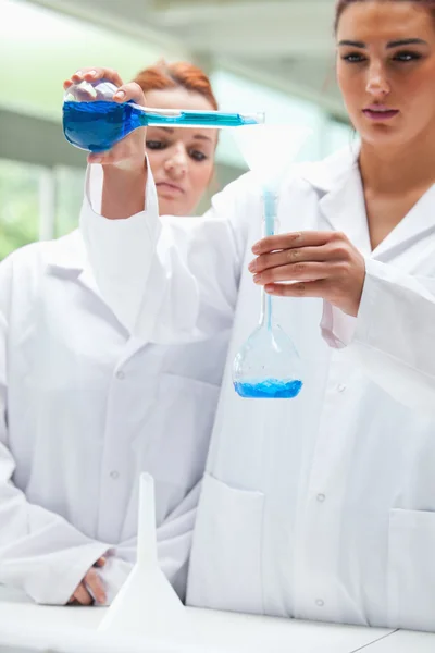 Retrato de cientistas derramando líquido em um frasco — Fotografia de Stock