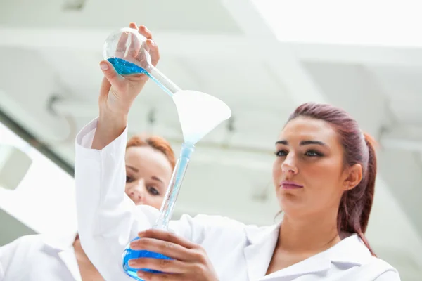 Scientist emptying a flask into another one — Stock Photo, Image