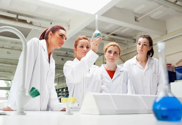 Science students looking at a liquid in a flask — Stock Photo, Image