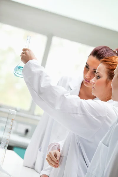 Cute chemistry students looking at a liquid — Stock Photo, Image