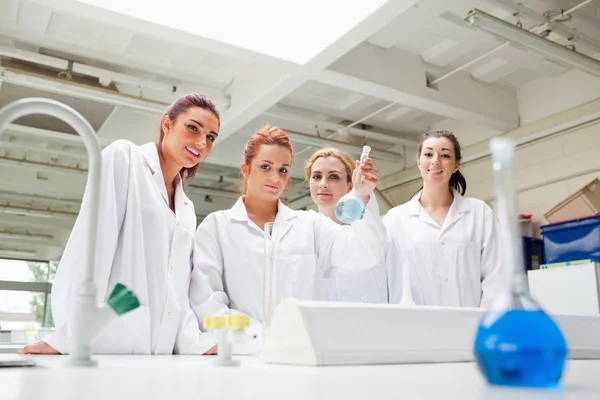 Улыбающиеся студенты химии держат фляжку — стоковое фото