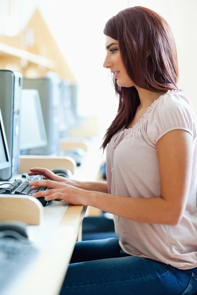 Retrato de uma estudante morena trabalhando com um computador — Fotografia de Stock