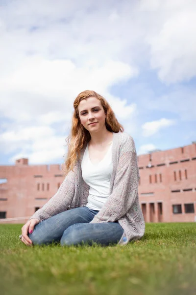 Portrait of a young woman sitting on a lawn — Stock Photo, Image