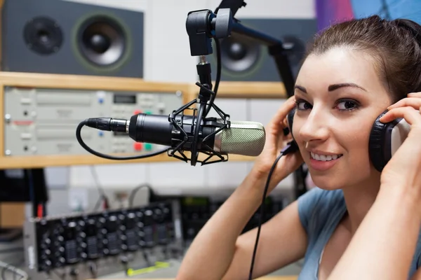 Jovem apresentadora de rádio colocando seus fones de ouvido — Fotografia de Stock