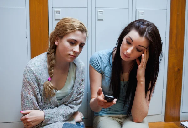 Sad student showing a text message to her friend — Stock Photo, Image