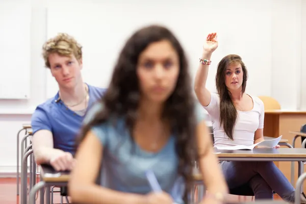 Student raising her hand to give an answer — Stock Photo, Image