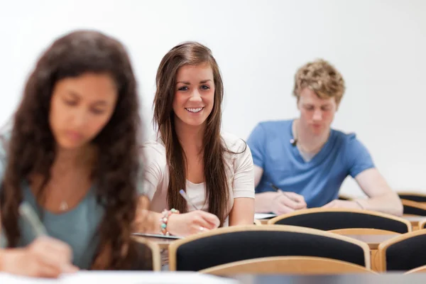 Usmívající se mladí studenti sedí na židli — Stock fotografie