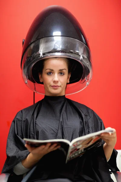 Portrait of a cute woman under a hairdressing machine — Stock Photo, Image